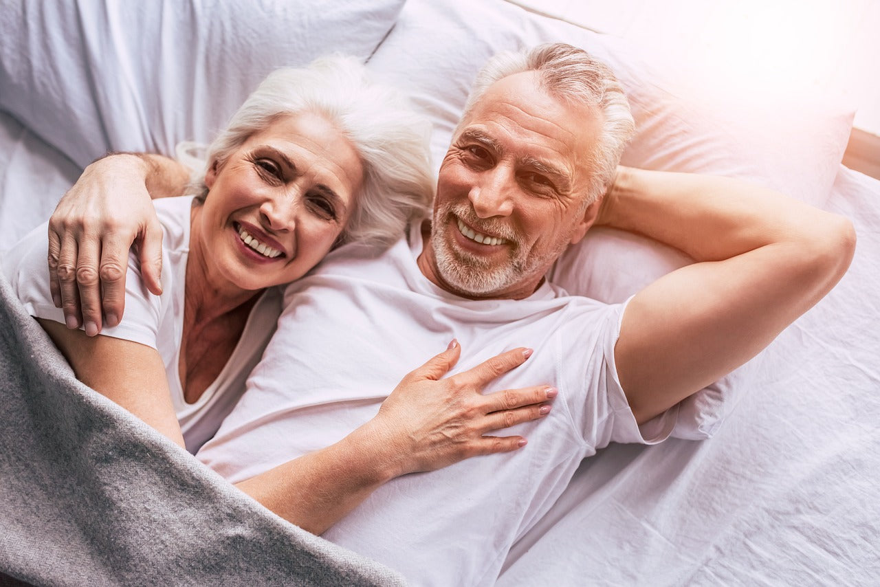 Couple senior souriant dans un lit – Ocliva